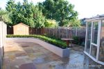 AFTER: New lawn and planting new fence and shed patio was constructed useing fossil sandstone in 4 sizes laid to a random pattern with a curved block planter wall painted in gun ship grey and planted with a topiary hedge.  