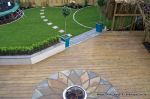 Garden was very unusable with Multiple steps from back doors new deck with inset sandstone sunflower feature was installed with new block rendered planter wall planted with topiary and linking circle lawns edged with granite setts and separate children's 