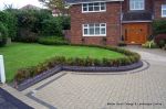 Driveway constructed using pewter grey paving with contrasting colour band and feature curved double row of kerbs with Topiary hedge to retain level change & inset LED lights