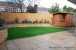 Low maintenance garden constructed with new Saxon paving, Curved planter wall using old stock buff bricks and single bull nose capping, artificial lawn & planting