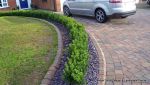 Driveway constructed using Marshall's Tegula paving with contrasting colour band and feature curved double row of kerbs with Topiary hedge to retain level change.