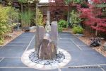 Small town house garden with a Japanese feel black limestone random paving installed with a centre slate water feature, Timber arbour constructed and garden planted with feature plants  