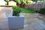 patio was constructed useing fossil sandstone in 4 sizes laid to a random pattern with a curved block planter wall painted in gun ship grey and planted with a topiary hedge.