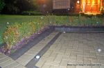 Driveway constructed using pewter grey paving with contrasting colour band and feature curved double row of kerbs with Topiary hedge to retain level change & inset LED lights