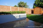 New lawn, planting, shed and fence patio was constructed using fossil sandstone in 4 sizes laid to a random pattern with a curved block planter wall painted in gun ship grey and planted with a topiary hedge.